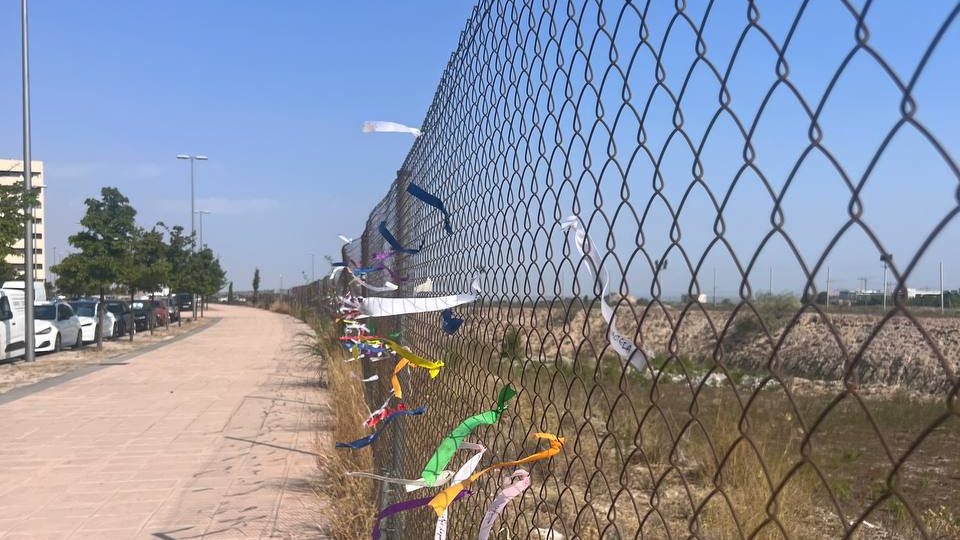 Valla de la parcela S-9 cubierta de lazos, junto al paseo del barrio